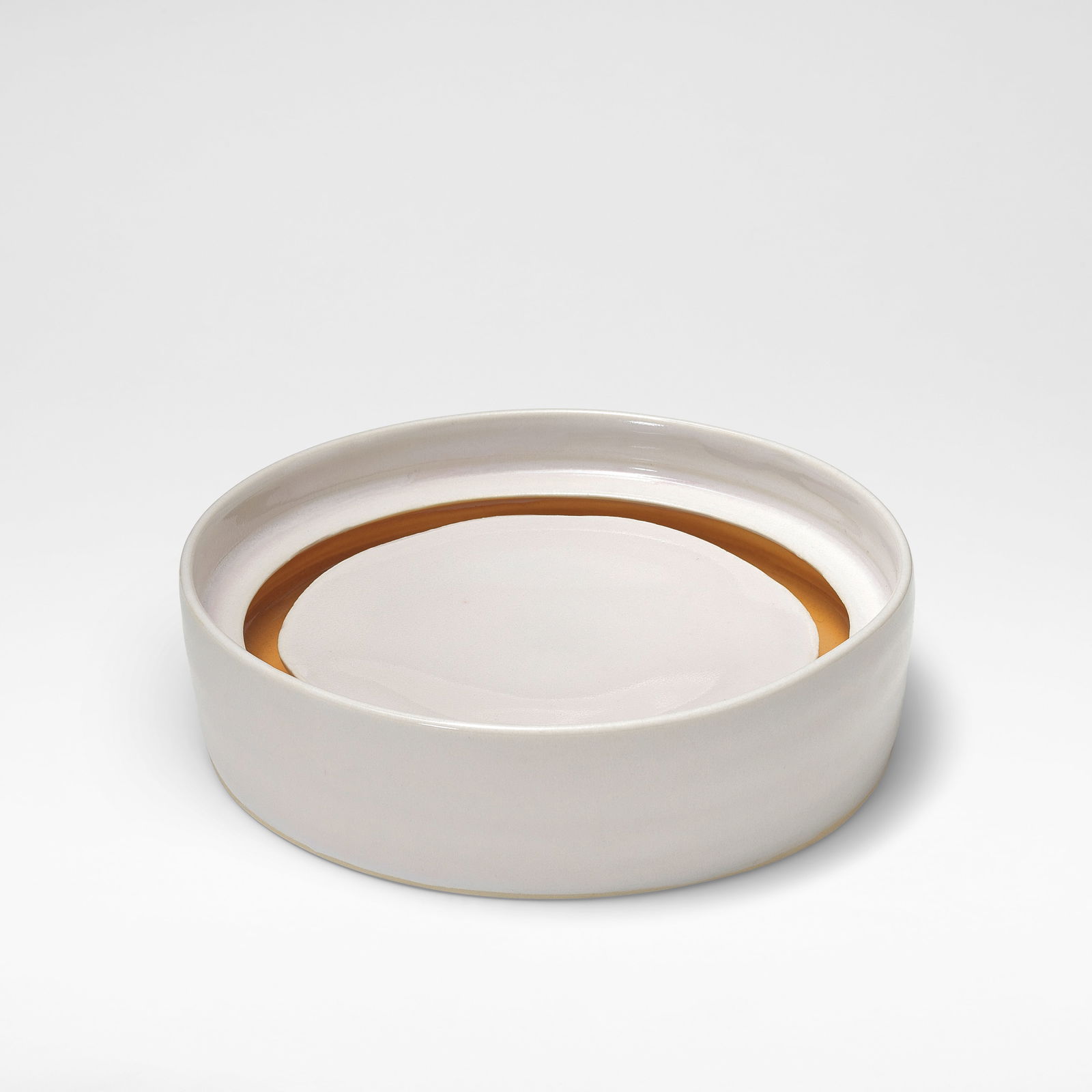 Edmund de Waal Low cylinder with floating base, circa 2002: Edmund de Waal Low cylinder with floating base, circa 2002 Porcelain, shiny white glaze, the centre of well with floating base and a shiny deep ochre glaze to the interior well. 5.5 cm high, 19.5 cm d