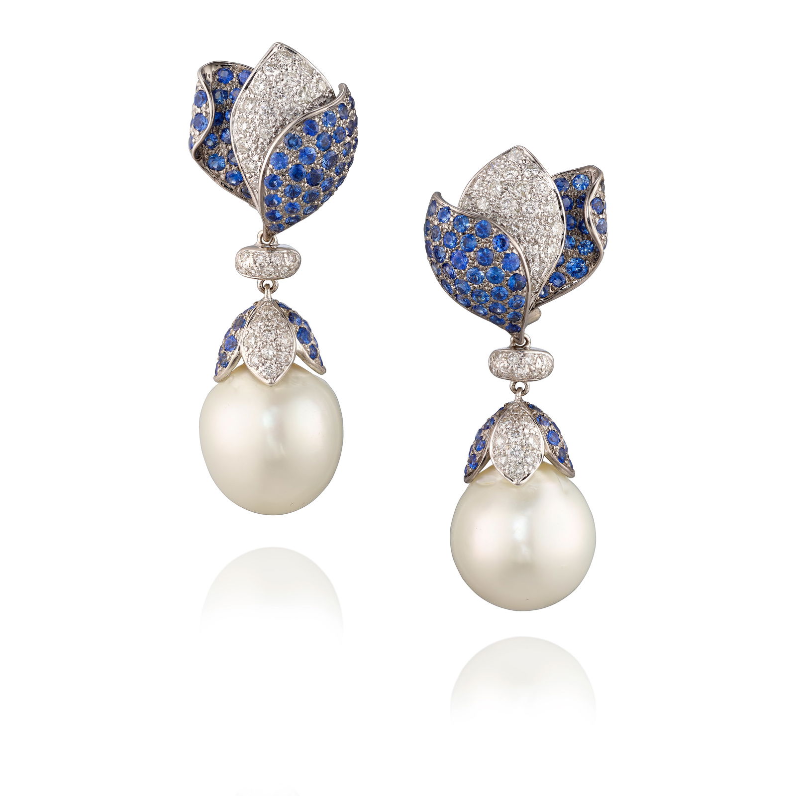 A PAIR OF 18K WHITE GOLD, CULTURED PEARL, SAPPHIRE AND DIAMOND EARRINGS: A PAIR OF 18K WHITE GOLD, CULTURED PEARL, SAPPHIRE AND DIAMOND EARRINGSOf floral design, suspending drop, semi-baroque cultured pearls, the petals pavé-set with round brilliant-cut sapphires and