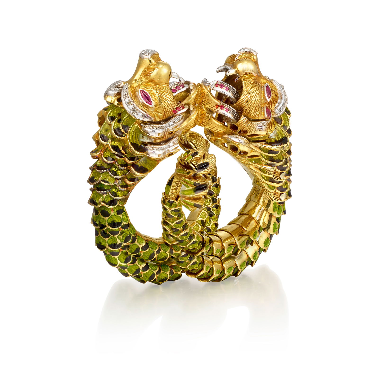 AN 18K BICOLOR GOLD, ENAMEL AND GEM-SET BRACELET: AN 18K BICOLOR GOLD, ENAMEL AND GEM-SET BRACELET Designed as two roaring lion's heads, accented across with single-cut diamonds, round and marquise-shaped rubies, the bodies of green and black enamel