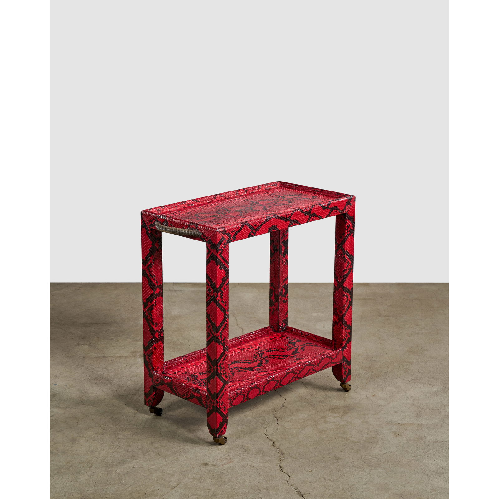 KARL SPRINGER (1931-1991) Telephone Style Side Table1977for Karl Springer Ltd., wood, red python...: KARL SPRINGER (1931-1991) Telephone Style Side Table 1977 for Karl Springer Ltd., wood, red python leather, horn handles and polished brass castors, metal label 'Karl Springer 1977' height 26 1/4in (6