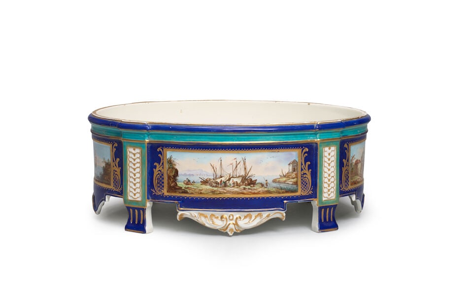 A porcelain jardinière, late 19th/20th century: A porcelain jardinière, late 19th/20th century Of oval form, decorated with rectangular panels of mercantile scene, framed in gold borders on a blue ground, spurious Sèrves mark to the
