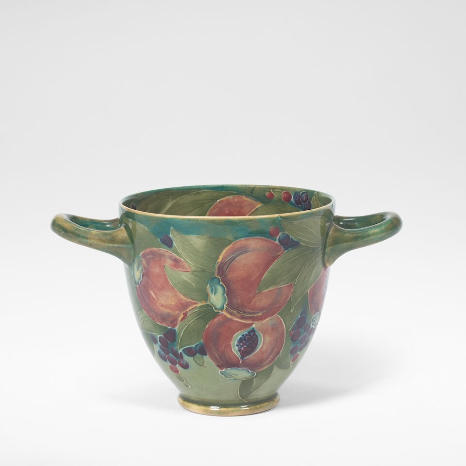 William Moorcroft Twin-handled 'Pomegranate' vase, circa 1915: William Moorcroft Twin-handled 'Pomegranate' vase, circa 1915 Glazed earthenware, tube-lined decoration of pomegranates amongst foliage in green, blue and red glazes. 10.3 cm high, 17 cm wide, 10.5
