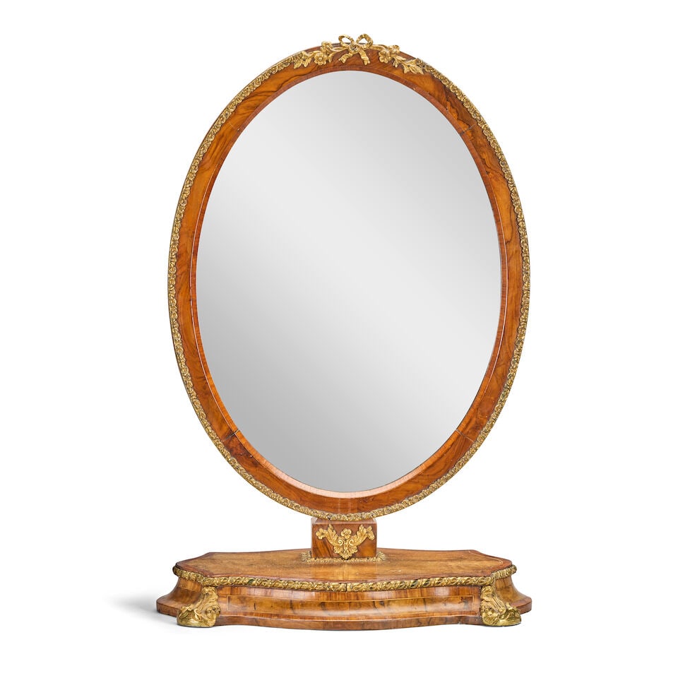A French early 20th century walnut, kingwood banded, and gilt metal mounted dressing mirror In t...: A French early 20th century walnut, kingwood banded, and gilt metal mounted dressing mirror In the Louis XVI style The hinged oval mirror plate on a moulded plinth base, 50cm wide x 35cm deep x 77cm
