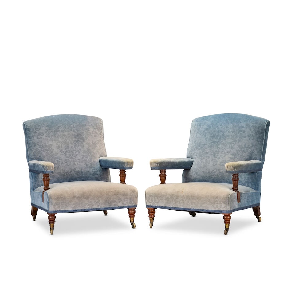 A pair of late Victorian walnut low or 'easy' armchairs by Howard and Sons 1890-1905 (2): A pair of late Victorian walnut low or 'easy' armchairs by Howard and Sons 1890-1905 Each with padded arms and tapering ring turned columnar arm terminals, on similar ribbed tapering front legs termin