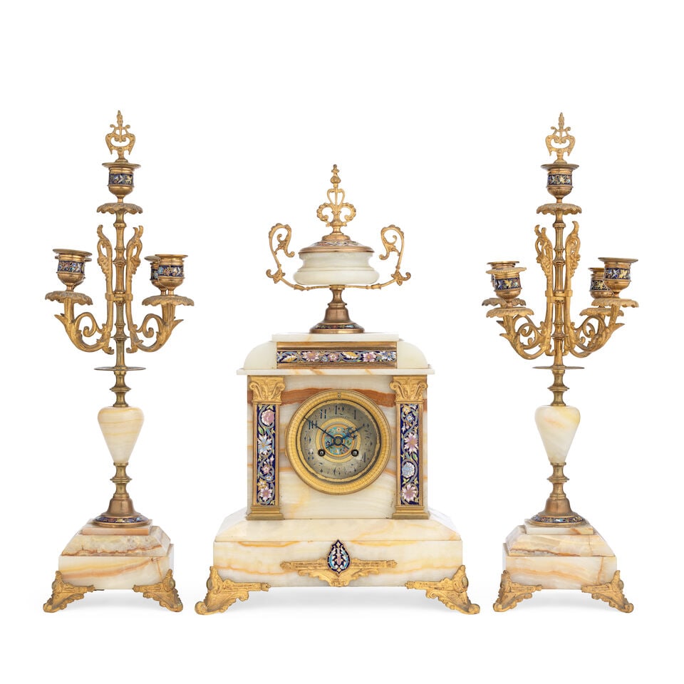 A late 19th century French gilt bronze and onyx and champlevé enamel clock garniture The d...: A late 19th century French gilt bronze and onyx and champlevé enamel clock garniture The dial indistinctly signed Laurens Fres, Béziers The arched rectangular case surmounted by a twin handl