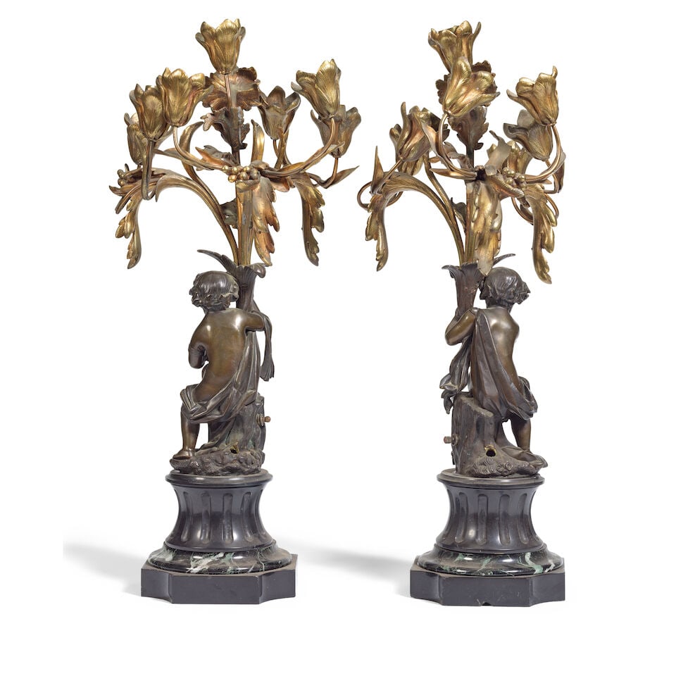 A pair of late 19th century French gilt and patinated bronze figural seven-light candelabra: A pair of late 19th century French gilt and patinated bronze figural seven-light candelabra The tulip scrolling arms issuing from cornucopia held by seated putti on swept, fluted and moulded black sla