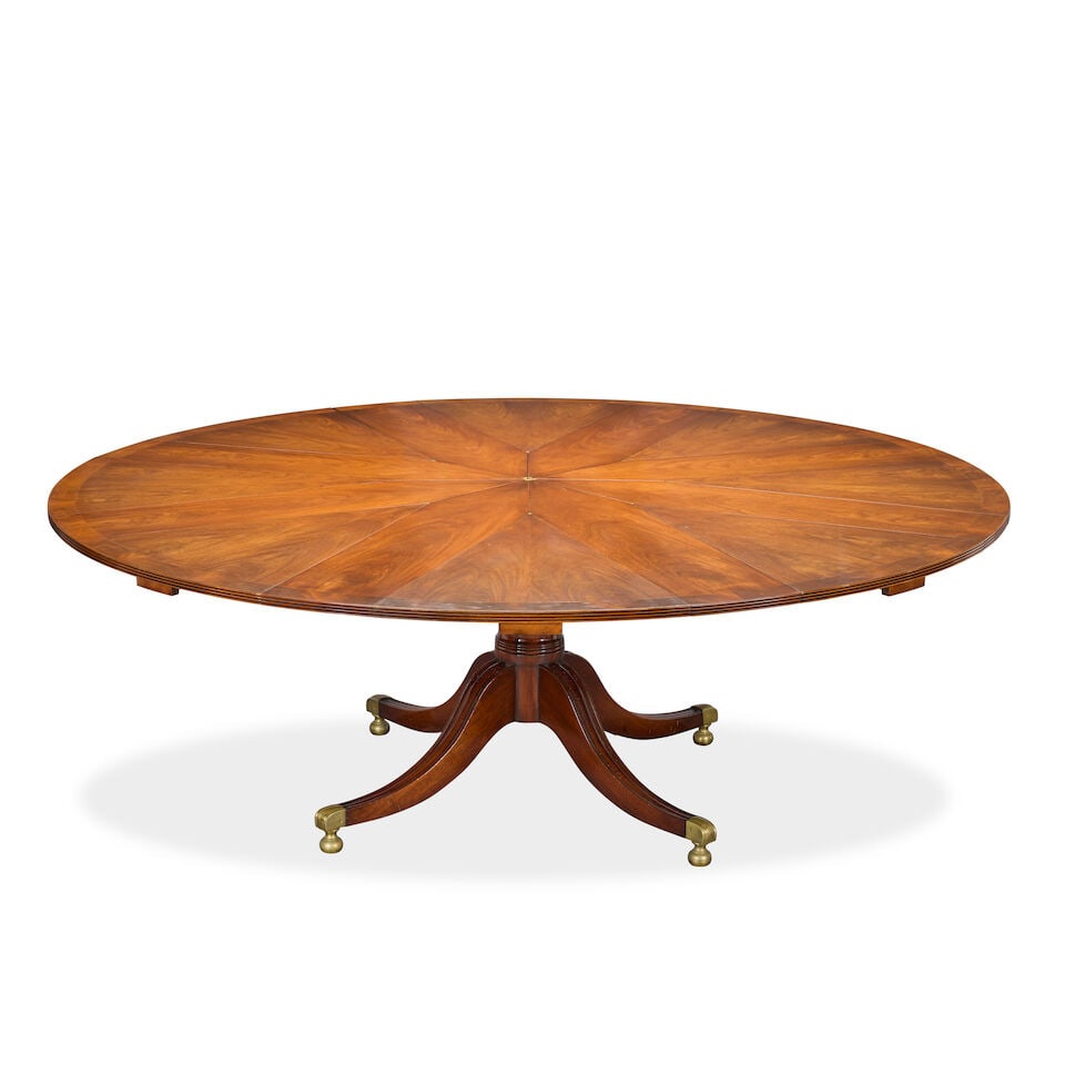 A mahogany 'Jupe' action extending circular dining table together with its leaf storage cabinet ...: A mahogany 'Jupe' action extending circular dining table together with its leaf storage cabinet Late 20th century, after the original Jupe patent extending table With a flame veneered and banded top,