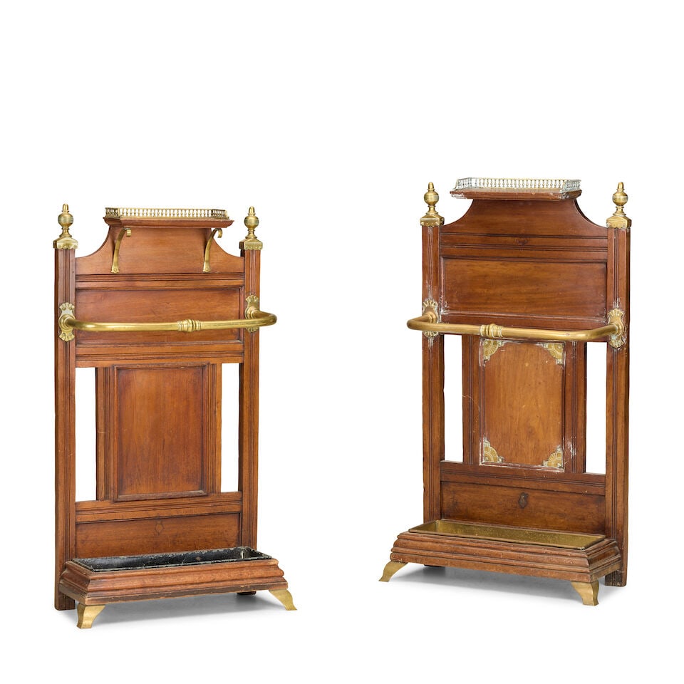 A near pair of Victorian oak and brass stick and umbrella standsAttributed to J. Shoolbred & Co....: A near pair of Victorian oak and brass stick and umbrella stands Attributed to J. Shoolbred & Co. With a gallery superstructure with a panelled back mounted with a brass guard above a painted tin inse