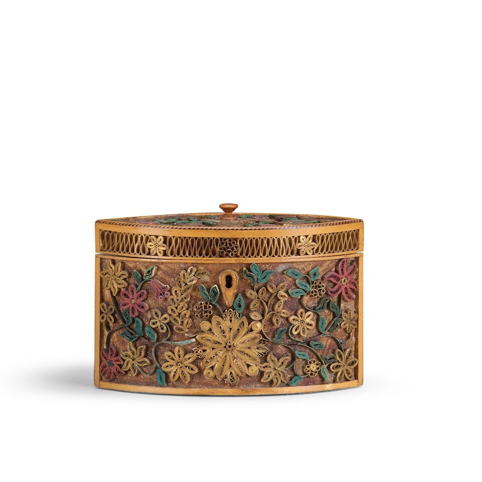 A George III scroll paper tea caddy Late 18th century: A George III scroll paper tea caddy Late 18th century Of oval form decorated with flowers and foliate scrolls, the hinged lid enclosing a fan inlaid top with brass handle, 19.5cm wide, 9.5cm deep, 13.