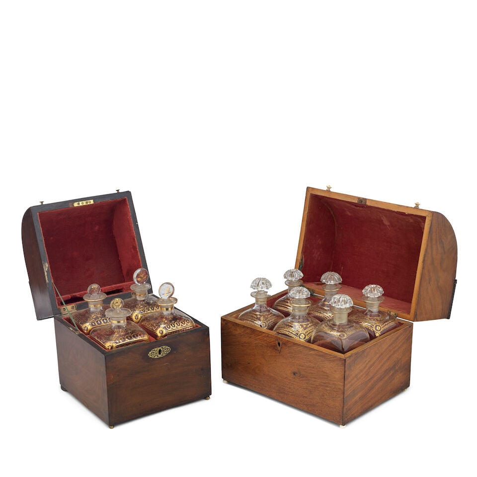Two George III mahogany decanter boxes Early 19th century (2): Two George III mahogany decanter boxes Early 19th century Each with hinged domed lids, one with an ivory handle and bun feet, enclosing six square, gilt-decorated clear glass bottles with later stoppe