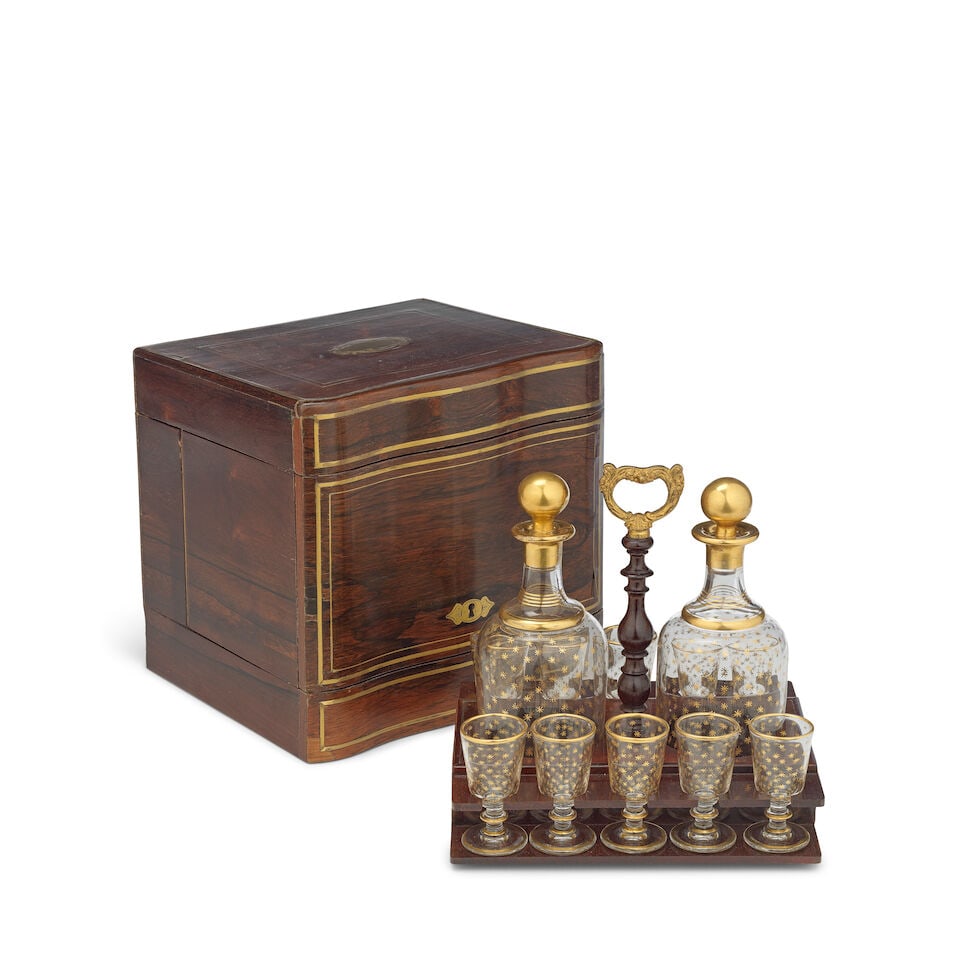 A French third quarter 19th century rosewood and brass inlaid decanter box In the Directoire style: A French third quarter 19th century rosewood and brass inlaid decanter box In the Directoire style The hinged top and sides enclosing a pull out tray with a pair of glass and gilt decorated decanters