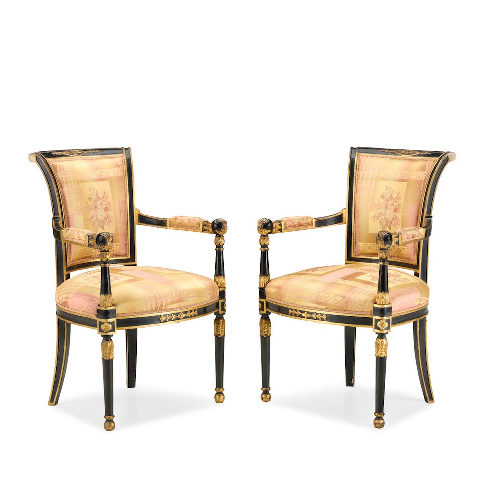 A pair of French ebonised and parcel gilt fauteuilsLate 19th century in the Empire style (2): A pair of French ebonised and parcel gilt fauteuils Late 19th century in the Empire style Recently upholstered in silk damask, the bowed back with flared and carved uprights on foliate carved tapering
