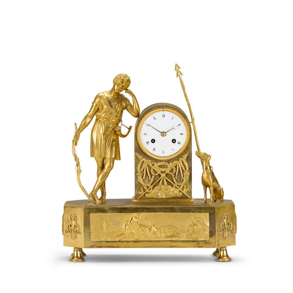 A early 19th century French gilt bronze mantel clock depicting 'Le Chasseur': A early 19th century French gilt bronze mantel clock depicting 'Le Chasseur' The resting hunter with bow in hand leaning on arched case enclosing an enamel Roman dial flanked by a hound and spear, on