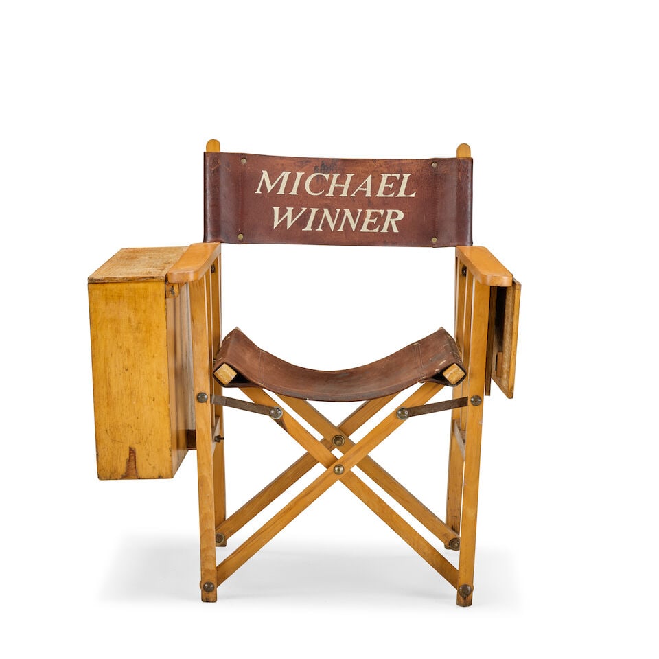 Michael Winner's Director's Chair Circa 1970 (2): Michael Winner's Director's Chair Circa 1970 With a folding oak and beech frame and brown leather seat and back, printed in white 'Michael Winner' on each side, with hinged table to left arm and scrip