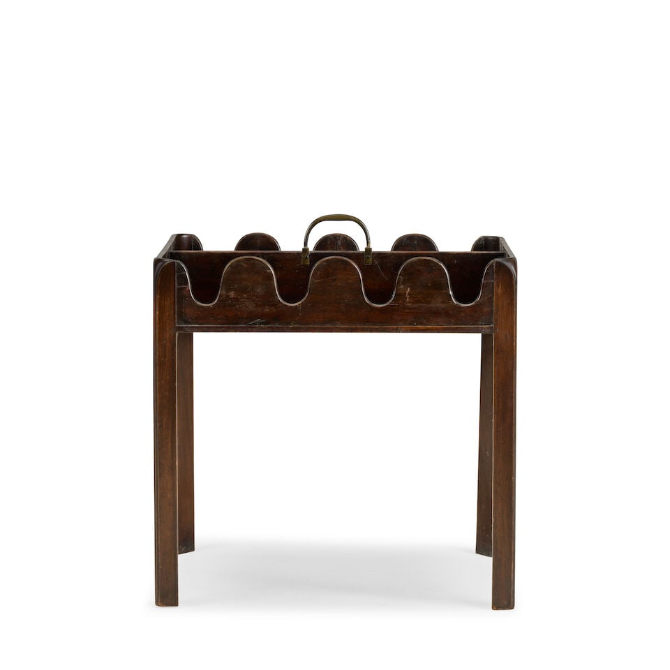 A mahogany wine bottle standEarly 20th century in the George III style: A mahogany wine bottle stand Early 20th century in the George III style The divided top with a brass carrying handle on chamfered moulded legs, 52cm wide x 38cm deep x 56cm high, (20in wide x 14 1/2in