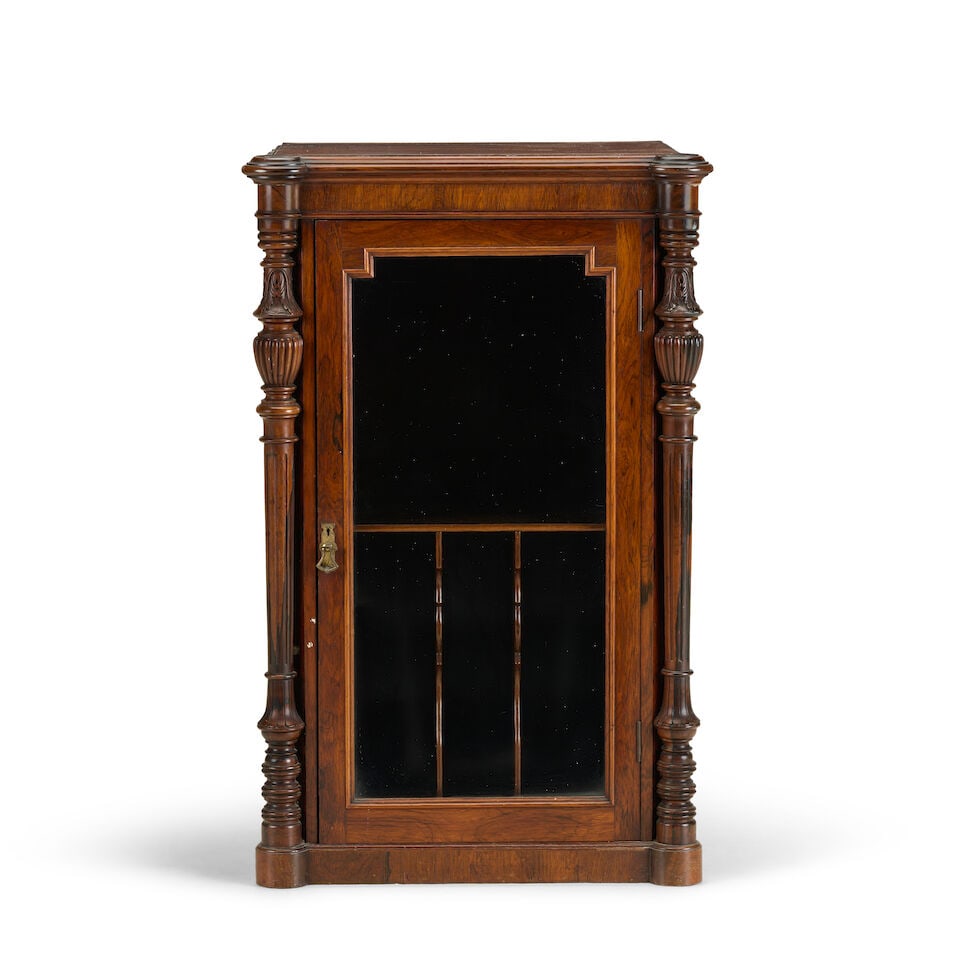 A Victorian rosewood music cabinet by Baxter & CompanyLate 19th century: A Victorian rosewood music cabinet by Baxter & Company Late 19th century With a glazed panelled door enclosing a divided interior for sheet music flanked by turned and carved columns on a plinth base,
