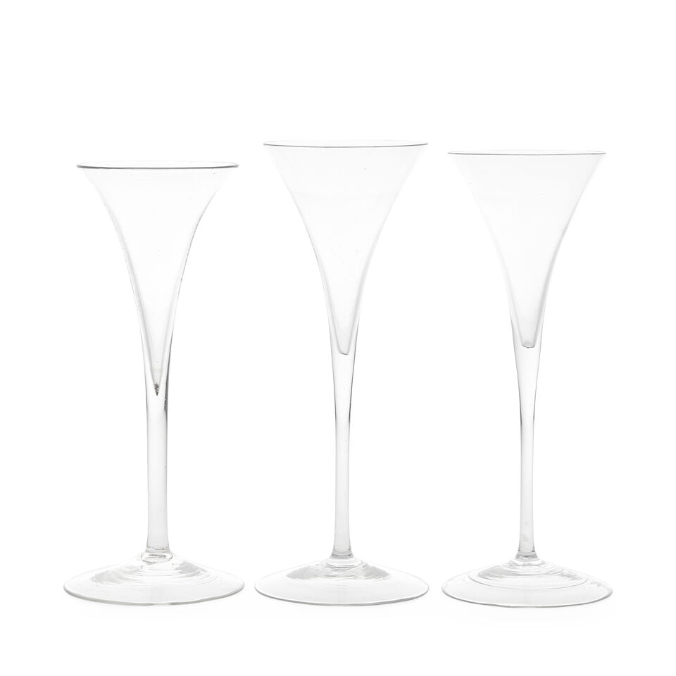 Three toasting glasses or wine flutes, circa 1740-50: Three toasting glasses or wine flutes, circa 1740-50 Of very slender drawn trumpet shape, the tall and extremely thin plain stems over delicate conical feet, 18.8cm to 19.7cm high (3) For further info