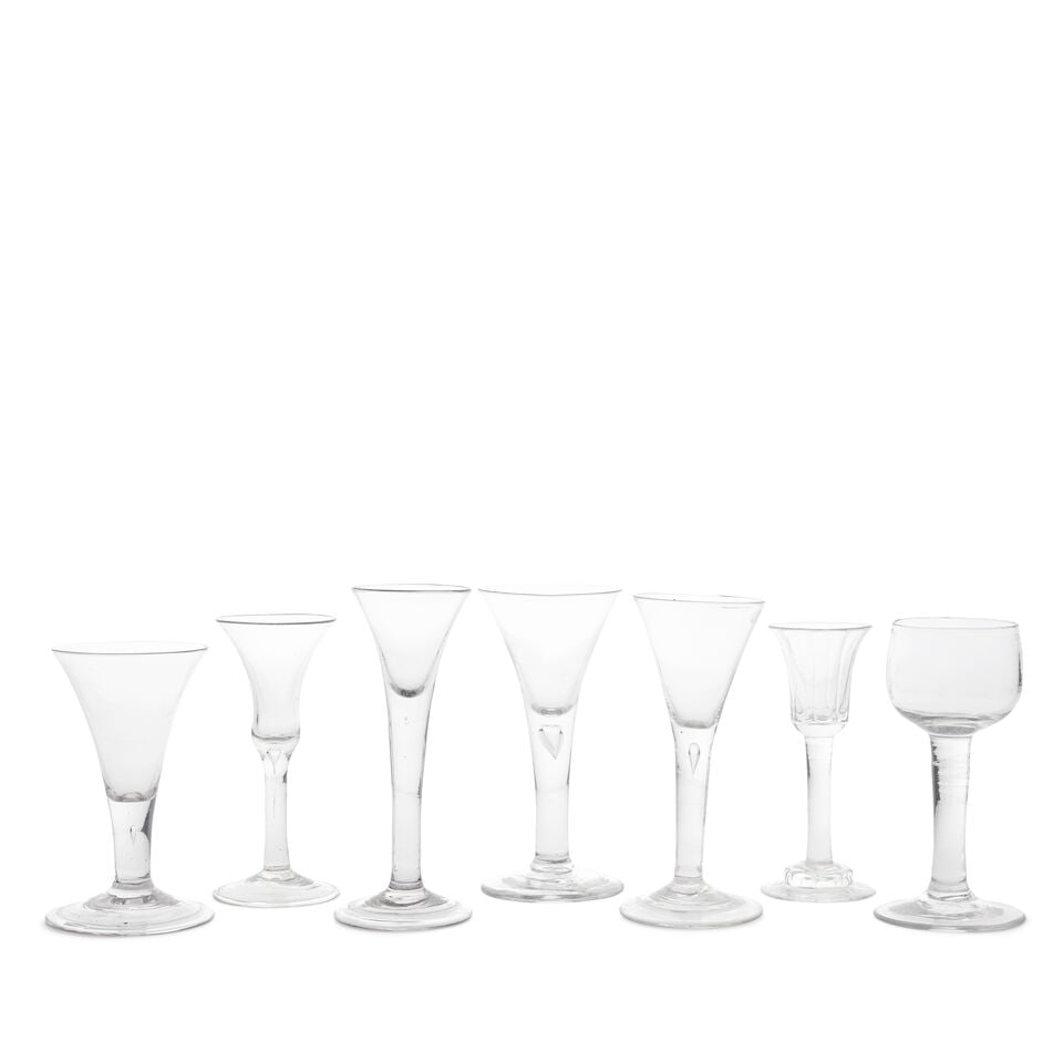 Six plain stem wine glasses and a mead or champagne glass, circa 1730-50: Six plain stem wine glasses and a mead or champagne glass, circa 1730-50 One with a small panel-moulded bell bowl and similarly moulded helmet foot, one with a waisted bell bowl on a teared stem and c