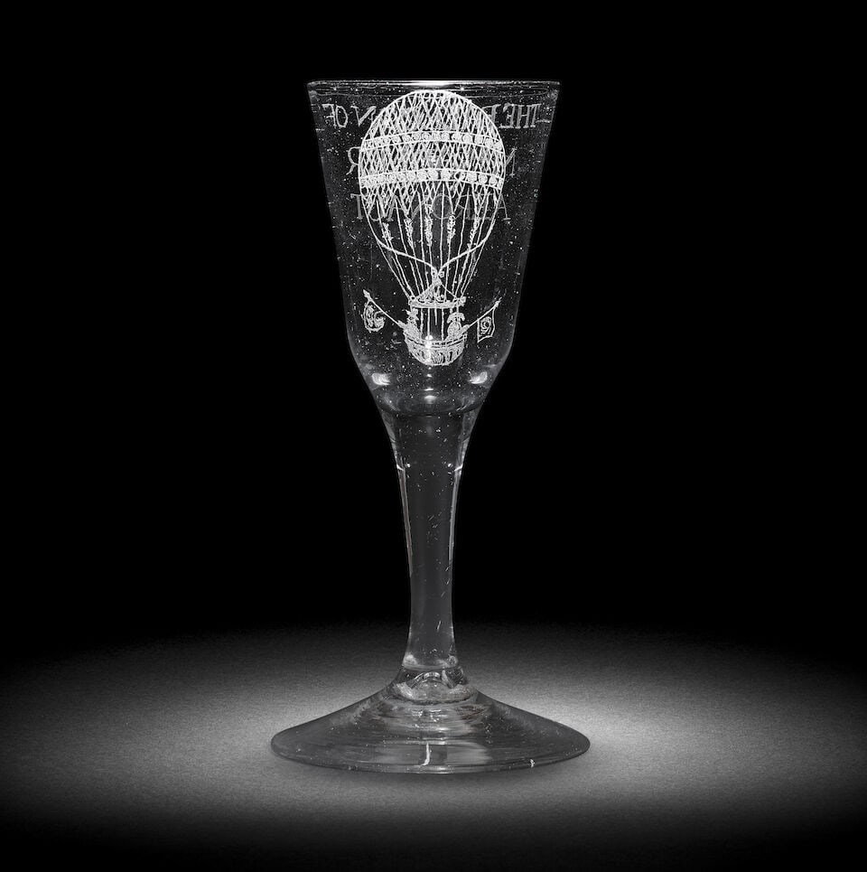 A rare engraved ballooning wine glass, the glass 18th century, the engraving circa 1811: A rare engraved ballooning wine glass, the glass 18th century, the engraving circa 1811 The tall ogee bowl decorated in diamond-point with two figures ascending in a hot air balloon, both holding flag