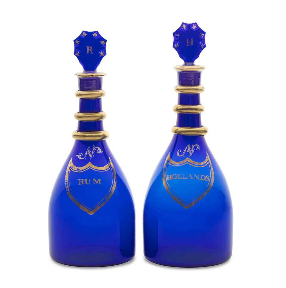 A fine pair of gilded blue glass decanters and stoppers, early 19th century: A fine pair of gilded blue glass decanters and stoppers, early 19th century Of 'taper' shape and in deep blue glass, reserved with gilt shield-shaped cartouches surmounted by the script initial N, ins