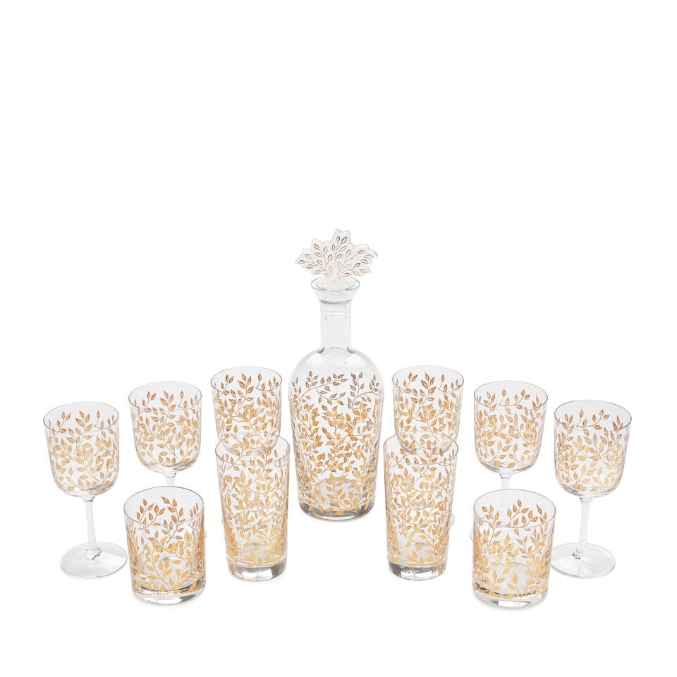 A part suite of Lalique gilded table glass, late 20th century: A part suite of Lalique gilded table glass, late 20th century Decorated with a profusion of leaves in gold, comprising a decanter with a stopper moulded as a tree, 32cm high, six wine glasses, 16.7cm