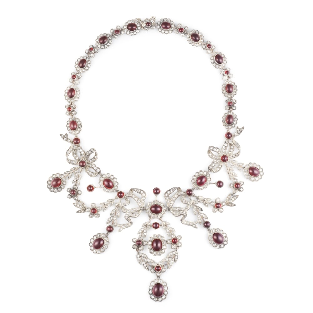 COLLIER GRENATS ET DIAMANTS: COLLIER GRENATS ET DIAMANTS Composé d'une succession de maillons articulés à motif floral, orné au centre de trois noeuds retenant en pampilles des guirlandes feuillagées, ser