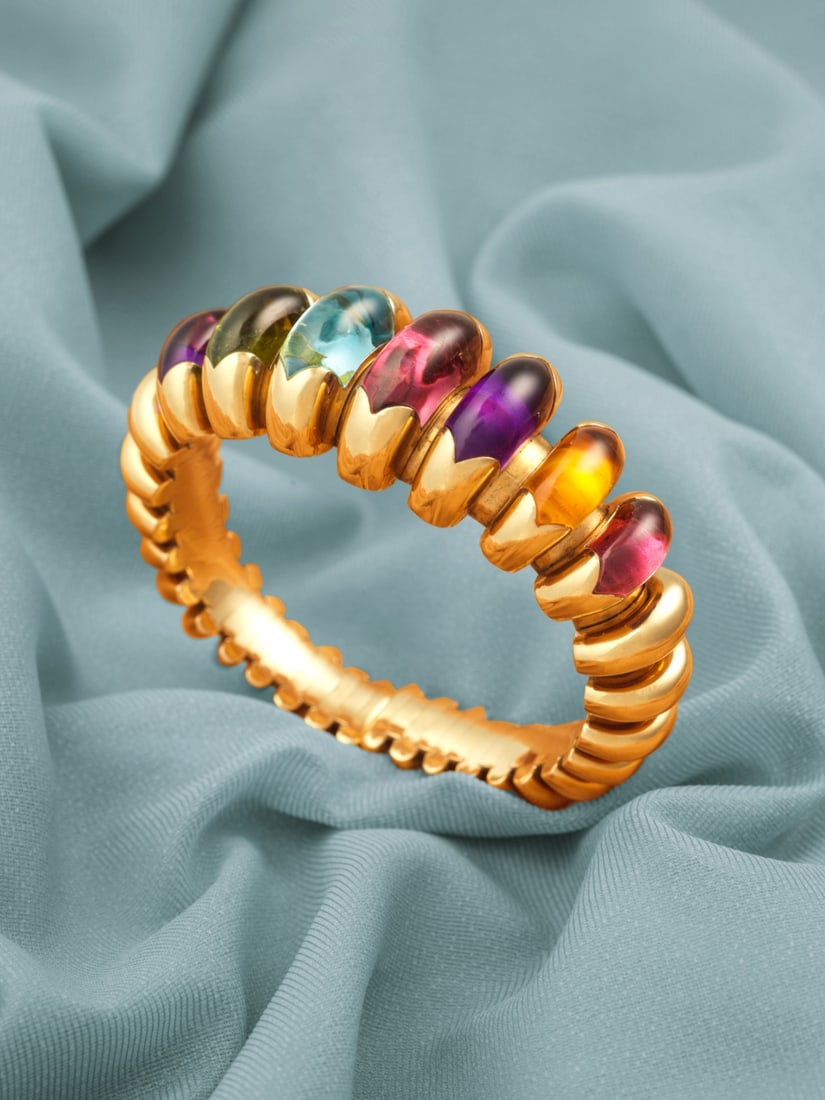 BULGARI: BRACELET JONC PIERRES DE COULEUR: BULGARI: BRACELET JONC PIERRES DE COULEUR Formant un motif godronné en or jaune, serti de cabochons de tourmalines roses, d'une tourmaline verte, d'améthystes, d'une topaze bleue et d'une ci