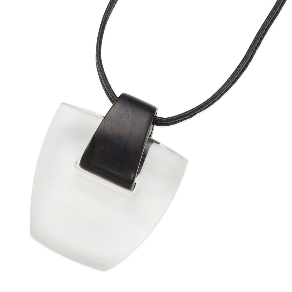 MONIES: LUCITE, EBONY, AND LEATHER PENDANT NECKLACE: MONIES: LUCITE, EBONY, AND LEATHER PENDANT NECKLACE • 1 trapezoid shape carved lucite measuring 3 1/8 in x 3 3/16 in x 9/16 in • 1 ebony wood bail measuring 2 in x 1 ¼ ind1