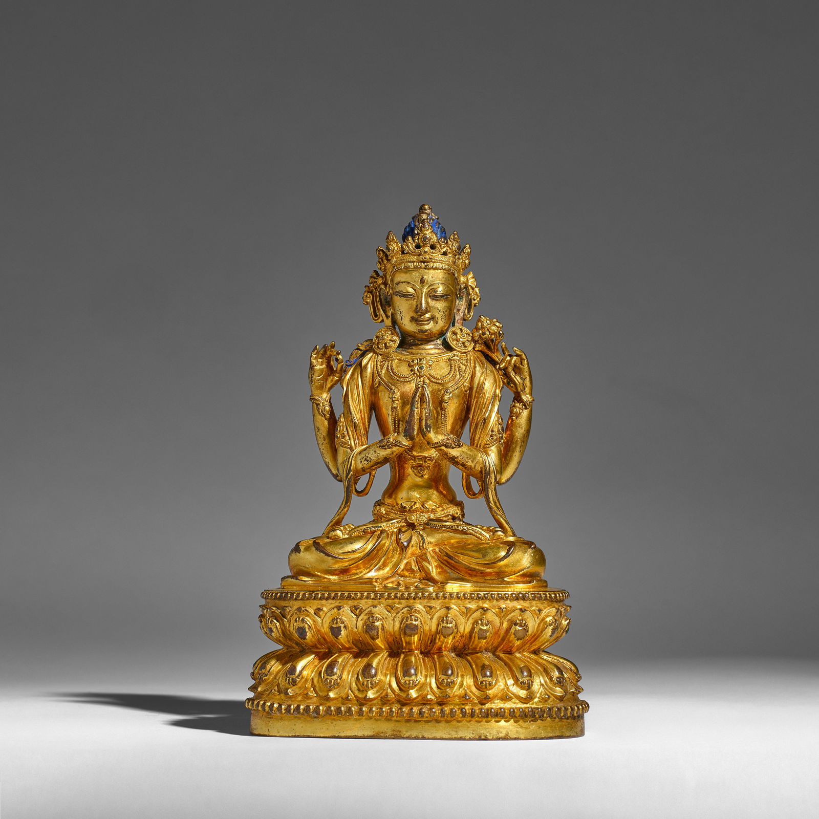 A GILT-BRONZE FIGURE OF FOUR-ARMED AVALOKITESVARA, SADAKSARI Yongle incised six-character mark a...: A GILT-BRONZE FIGURE OF FOUR-ARMED AVALOKITESVARA, SADAKSARI Yongle incised six-character mark and of the period Seated in vajraparyanksana on a double lotus pedestal base, with principal hands in anj