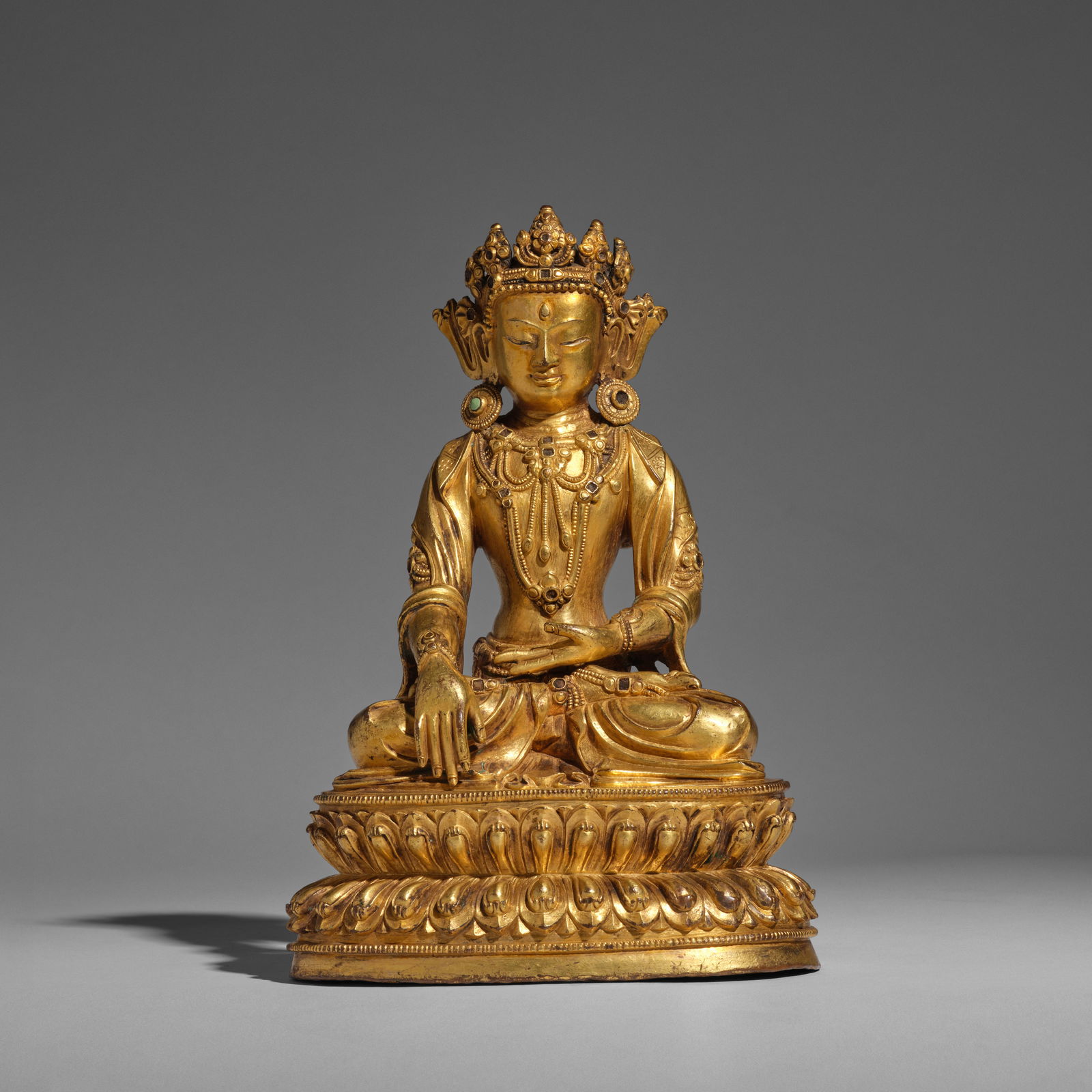 A GILT-BRONZE FIGURE OF BUDDHA SAKYAMUNI 17th/18th century (brocade fitted box): A GILT-BRONZE FIGURE OF BUDDHA SAKYAMUNI 17th/18th century Finely cast seated on a double-lotus beaded base with legs crossed in dhyanasana, the left hand rested on the lap in dhyanamudra and the righ