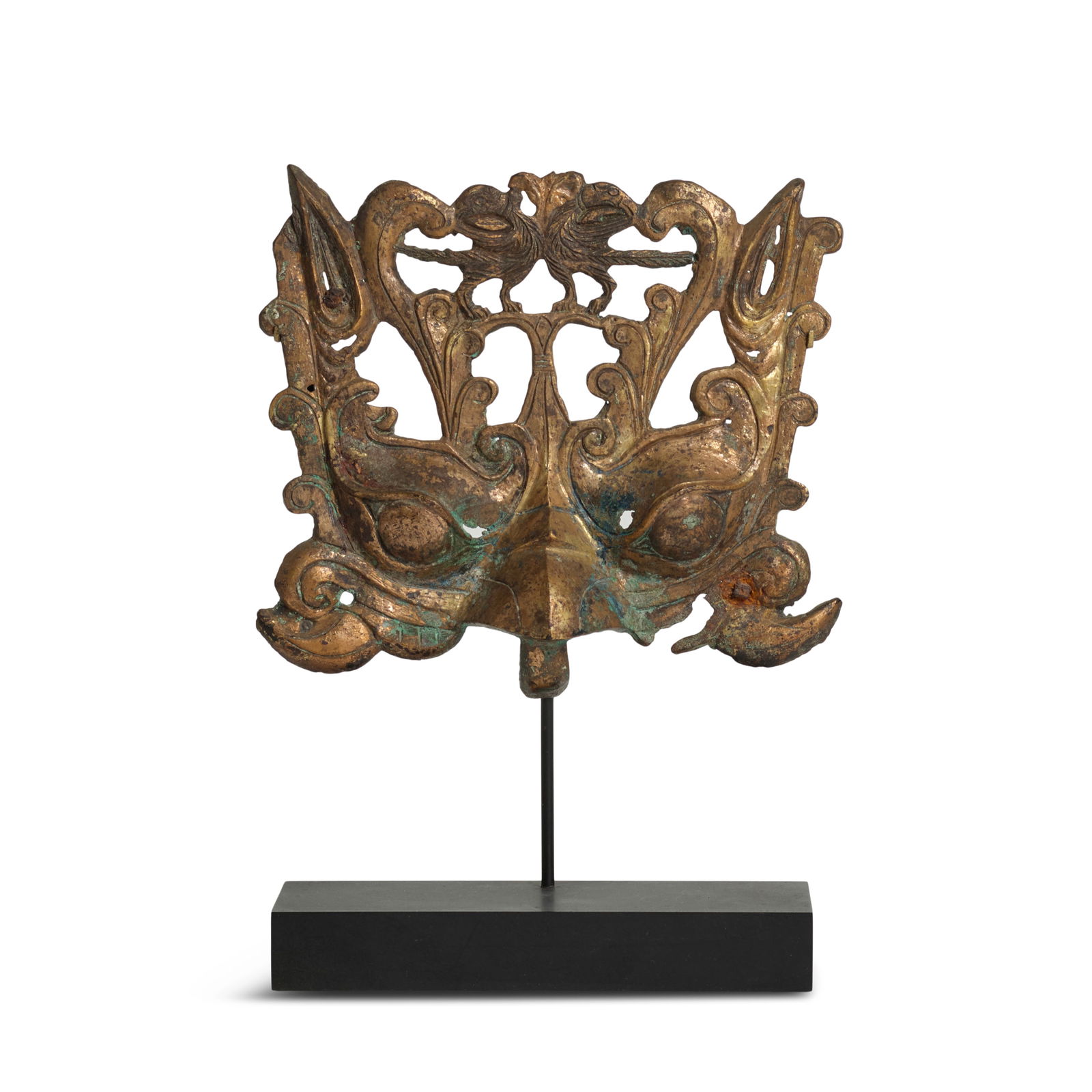 A GILT BRONZE 'MYTHICAL BIRD' MASK Northern Wei Dynasty, 5th century (metal stand): A GILT BRONZE 'MYTHICAL BIRD' MASK Northern Wei Dynasty, 5th century Cast in high relief openwork, the large bulging eyes and prominent beak framed by curled uprising curls and pricked ears, the crest