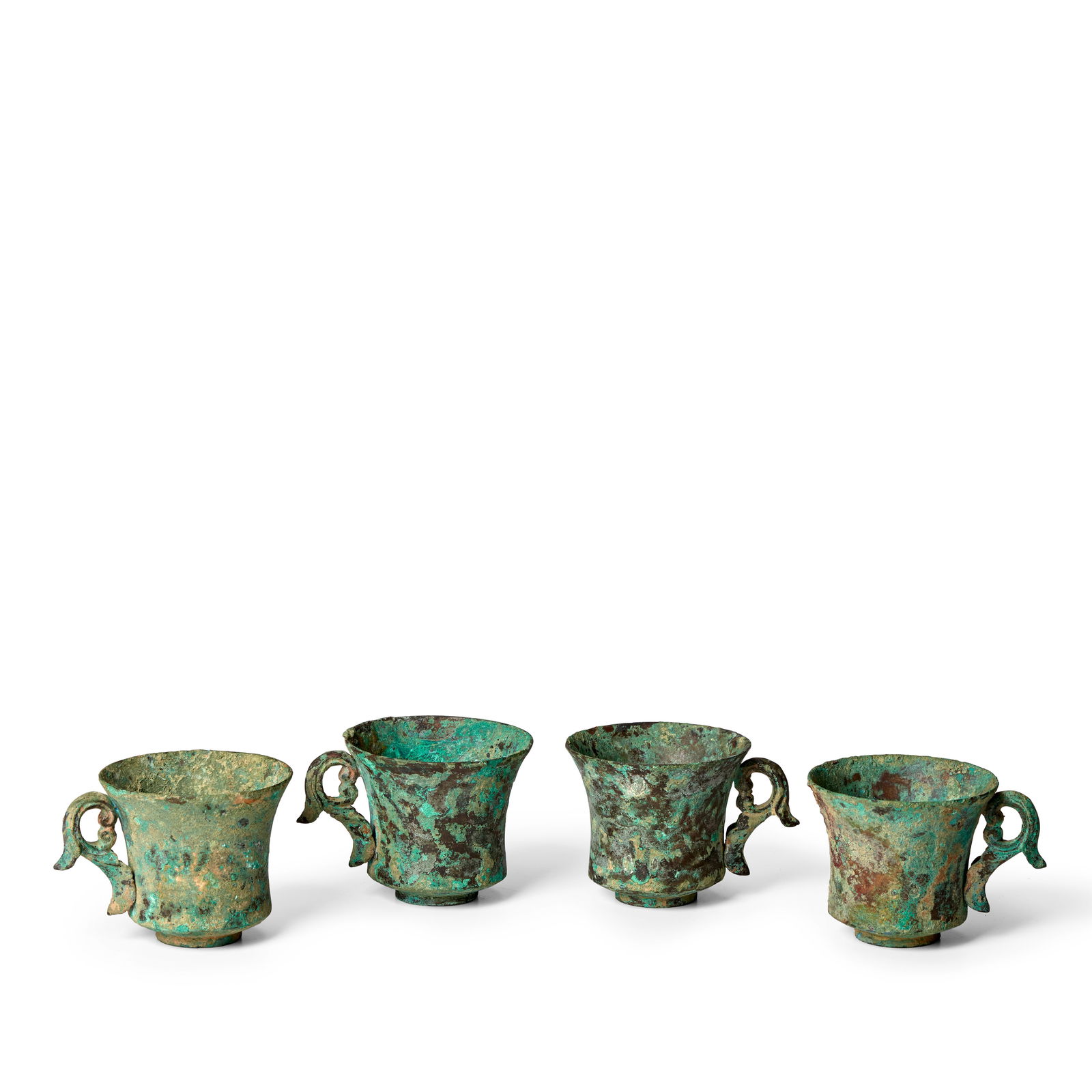 A GROUP OF FOUR BRONZE HANDLED CUPS Tang Dynasty (4): A GROUP OF FOUR BRONZE HANDLED CUPS Tang Dynasty Each deep cylindrical cup with flaring mouth and angled base, attached with a finely cast 'scrolling leaf' handle to one side, all supported by a short