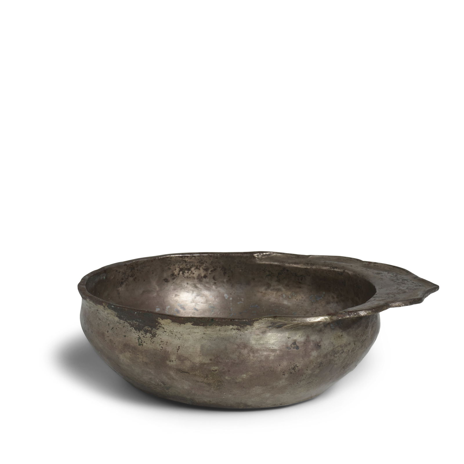 AN EARLY SILVER FLANGE-HANDLED SILVER SHALLOW DRINKING BOWL Jin/Yuan Dynasty: AN EARLY SILVER FLANGE-HANDLED SILVER SHALLOW DRINKING BOWL Jin/Yuan Dynasty The plain shallow cup is undecorated save for a raised edge on the ogival foliate flange handle that extends horizontally f
