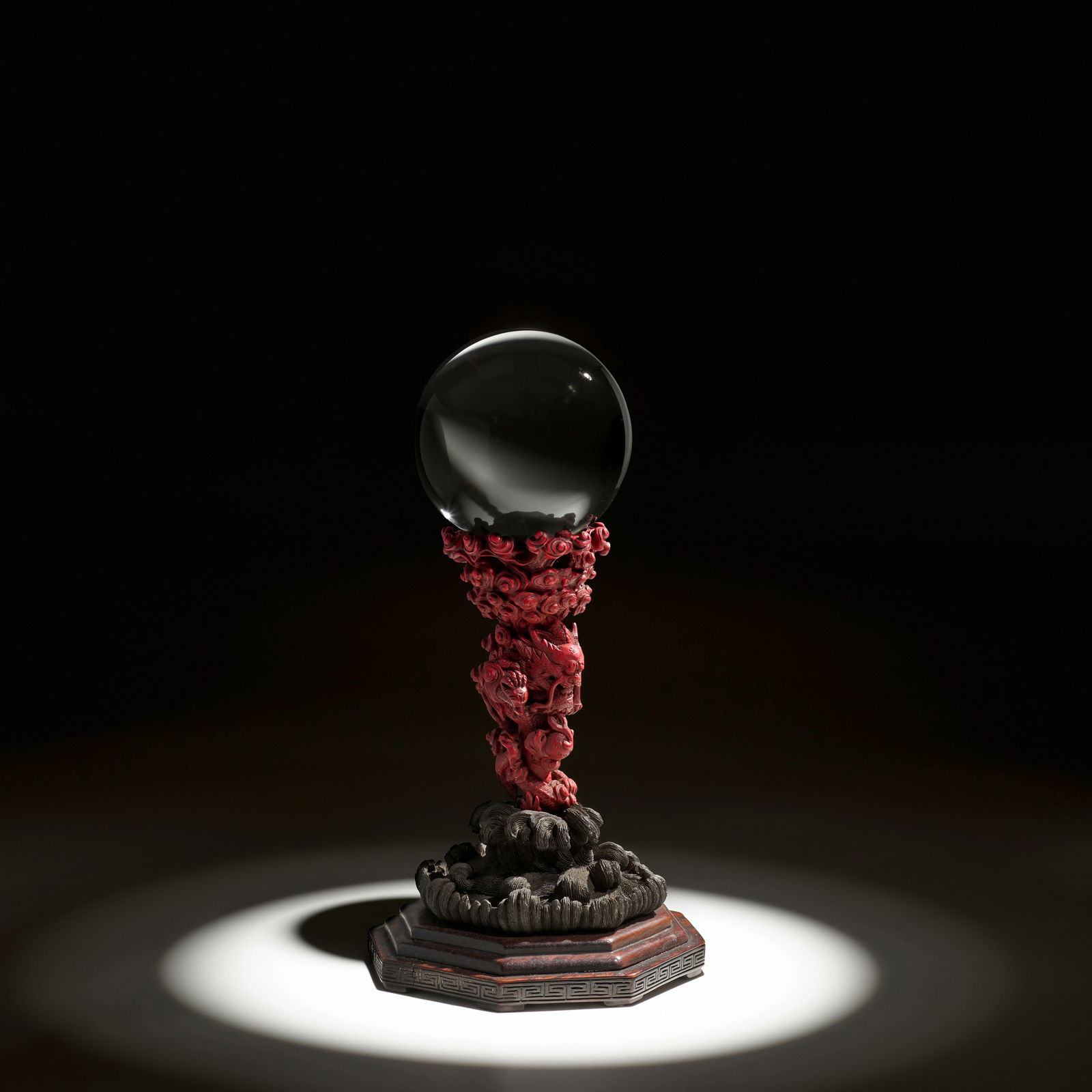 AN EXTREMELY RARE CINNABAR LACQUER AND WOOD 'DRAGON AND FLAMING PEARL' STAND AND CLEAR CRYSTAL S...: AN EXTREMELY RARE CINNABAR LACQUER AND WOOD 'DRAGON AND FLAMING PEARL' STAND AND CLEAR CRYSTAL SPHERE Qianlong, 1736-1795, probably Imperial The cinnabar lacquer stand beautifully carved in extreme hi