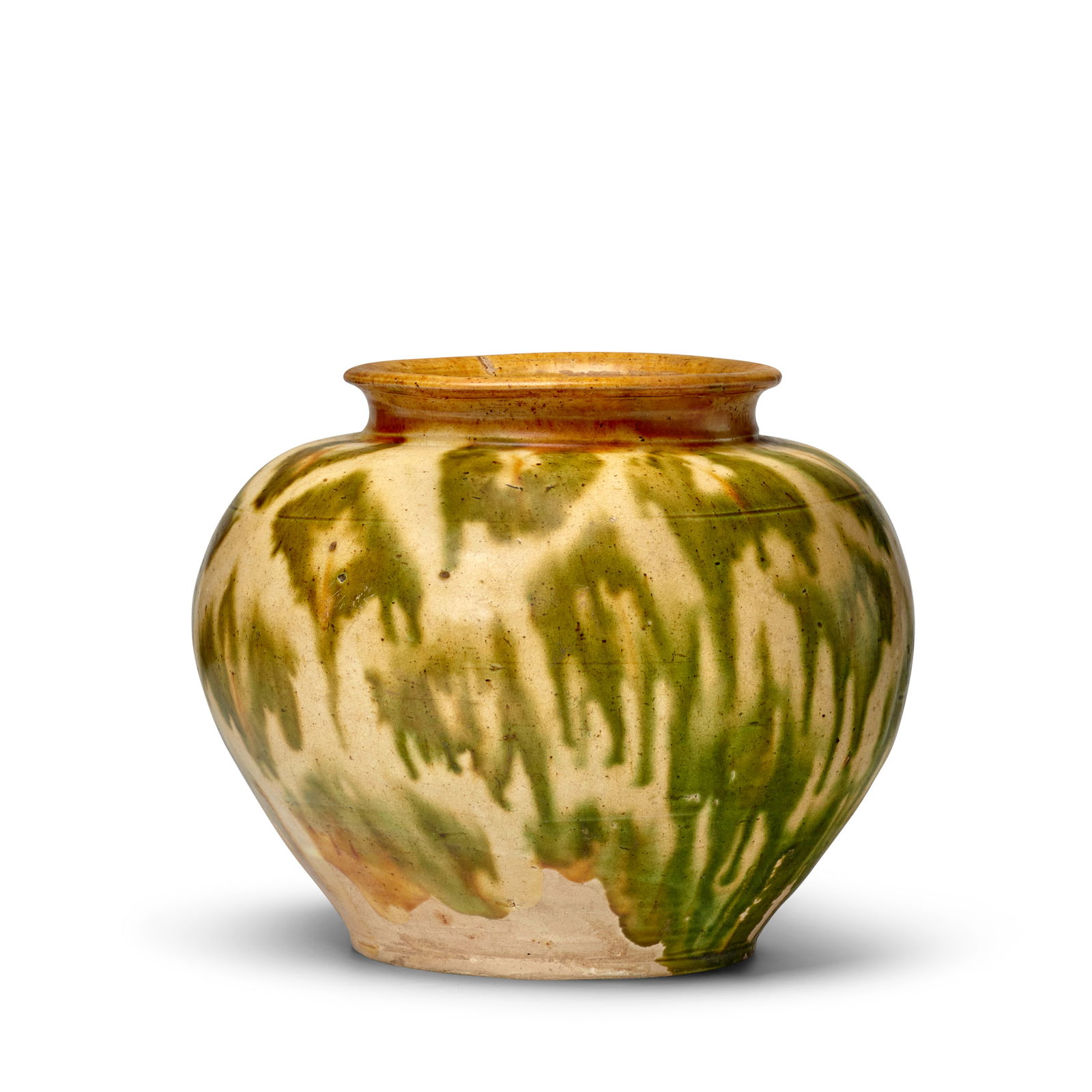 A SANCAI-GLAZED POTTERY JAR Tang Dynasty: A SANCAI-GLAZED POTTERY JAR Tang Dynasty The compressed globular body surmounting a short neck and everted rim, decorated with green and ocher splashes under a clear glaze, the lower body and flat bas