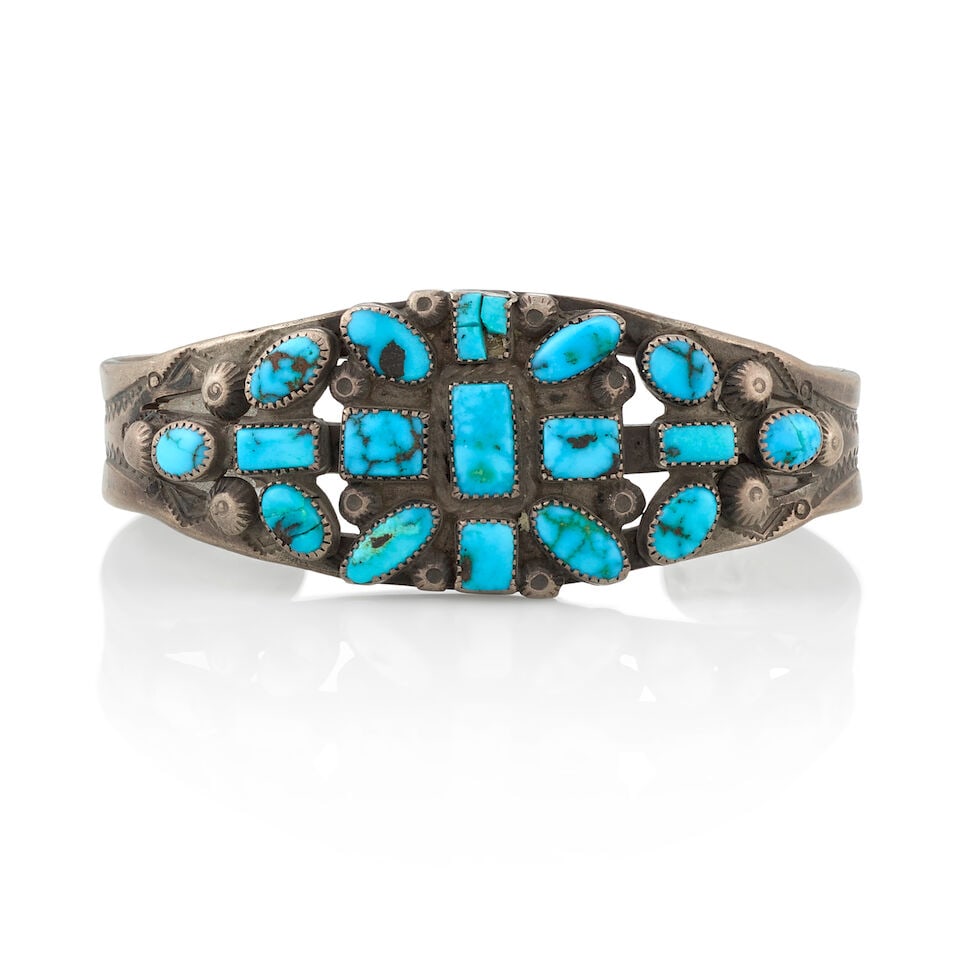 A Diné (Navajo) or Zuni cuff bracelet: A Diné (Navajo) or Zuni cuff bracelet A stamped and pierced silver cuff set with an arrangement of oval and rectangular-shaped turquoise, with silver button accents. inner circumference