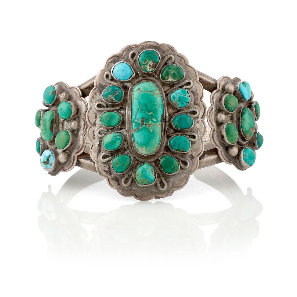 A Diné (Navajo) cuff bracelet: A Diné (Navajo) cuff bracelet Designed with a pair of carinated wires supporting scalloped conchas supporting clusters of turquoise separated by wire or silver dop accents. inner circumference
