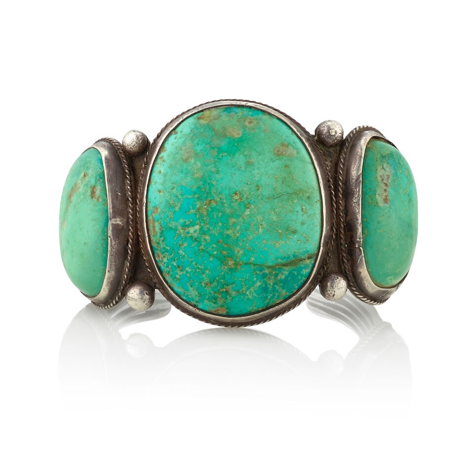A Diné (Navajo) cuff bracelet: A Diné (Navajo) cuff bracelet Constructed of five thin wires supporting three large rounded turquoise stones separated by pairs of silver balls. inner circumference (including gap) 6 13/16in, gap