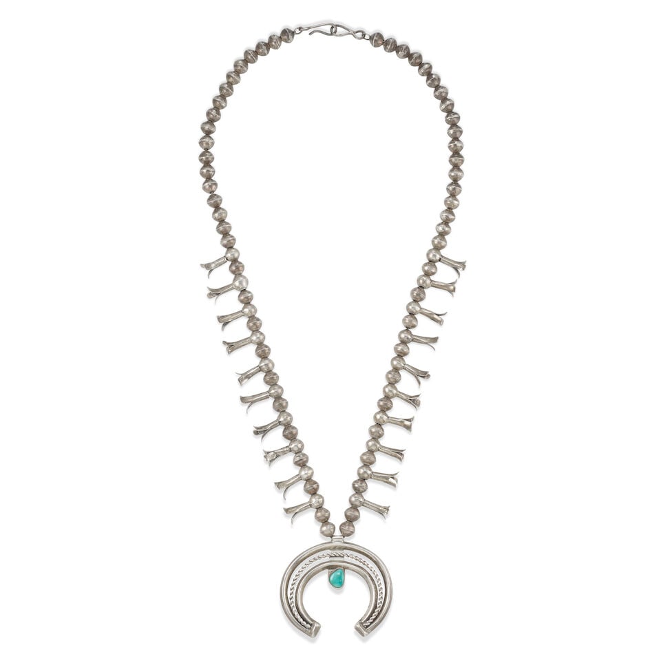 A Diné (Navajo) squash blossom necklace: A Diné (Navajo) squash blossom necklace A petite example, designed with a single strand of silver beads interspersed with ten simple blossoms and suspending a carinated and twisted wire naja set