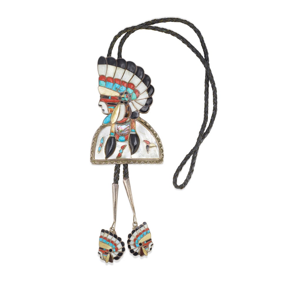 A Roger and Lela Cellicion figural multi-stone inlaid bolo tie: Roger and Lela Cellicion Zuni, (1941-2007) and (1941-2009), late 1950s/early 1960s, a large figural bolo tie depicting a man in headdress in profile, of silver set with a variety of stones including