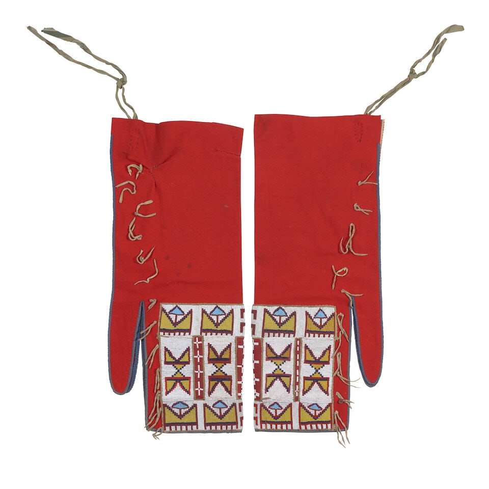 Pair of Niitsitapi (Blackfeet) beaded leggings: Pair of Niitsitapi (Blackfeet) beaded leggings Of red wool with cotton piping, with applied geometric beaded panels about the lower third flanking partially beaded areas. each approximately: length