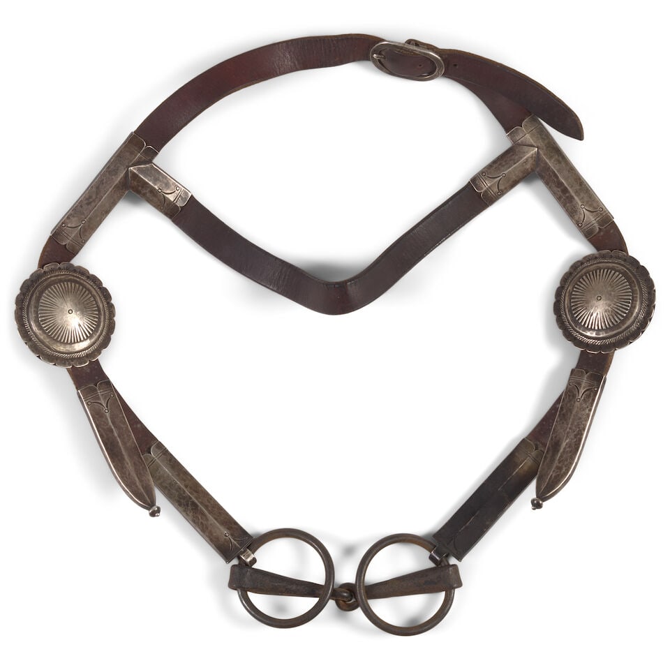A Taos silver headstall: A Taos silver headstall Of typical form with stamped cheek bands and conchas, the buckle stamped: TAOS, with second mark on opposite side, likely: M, mounted on leather and attached with a snaffle