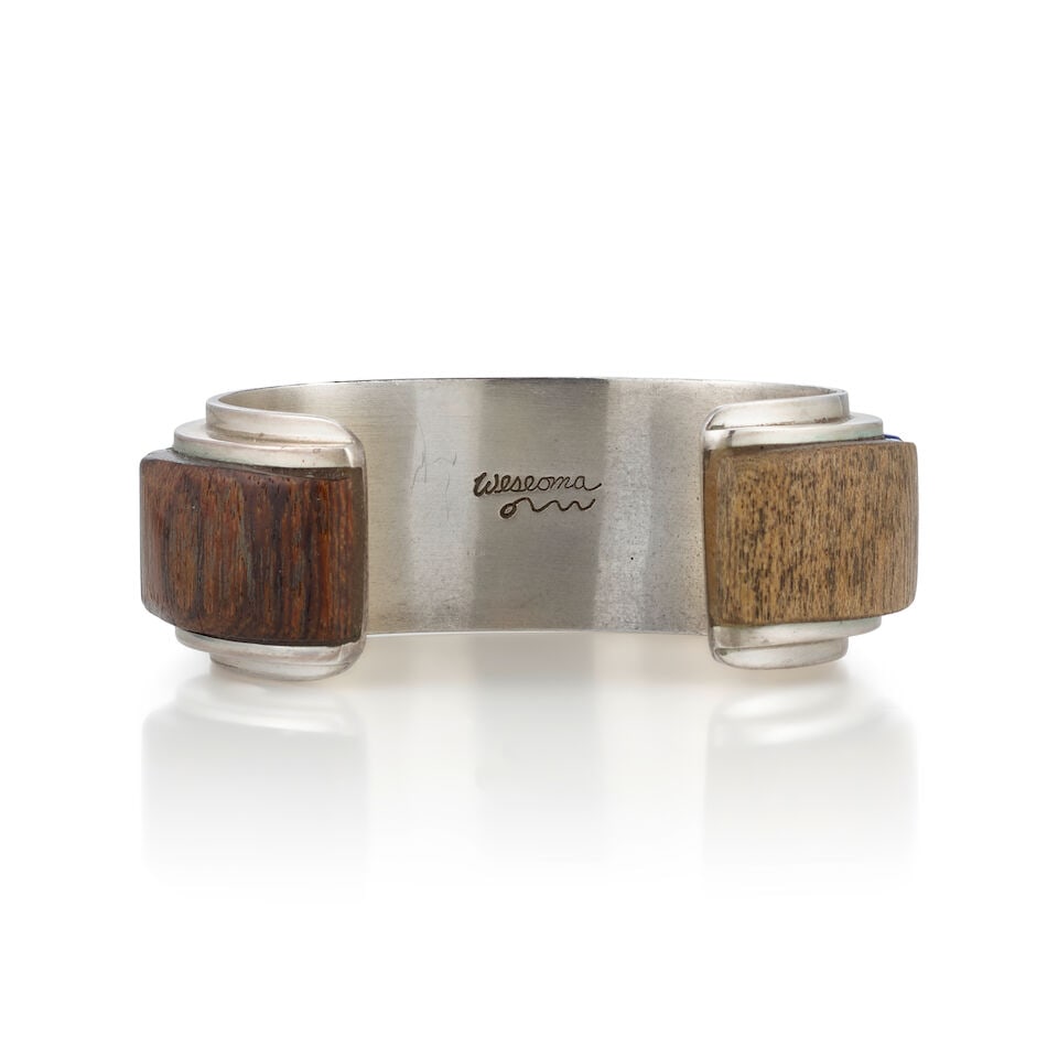 A Phillip Sekaquaptewa cuff bracelet: Phillip Sekaquaptewa Hopi, (1948-2003), a sterling silver cuff bracelet with cobblestone inlay of turquoise and lapis, silver spacers, wood bands at the terminals, signed 'Weseoma' and with pictograph