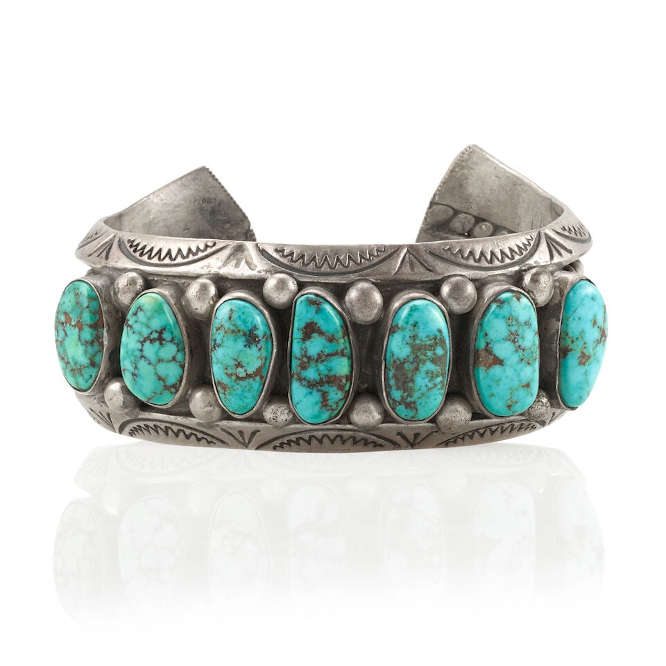 A Diné (Navajo) cuff bracelet: A Diné (Navajo) cuff bracelet A heavy example, of stamped carinated, rounded and twisted wire supporting seven turquoise separated by silver drops, with hammered terminals. inner circumference