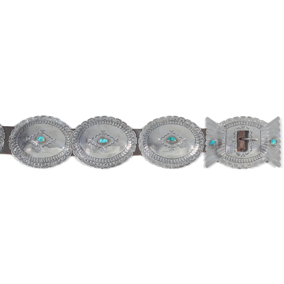 A Diné (Navajo) concha belt: A Diné (Navajo) concha belt Designed with oval-shaped stamped and scalloped conchas, each set with an oval turquoise, the winged buckle set with two turquoise. length overall 43in, each concha: