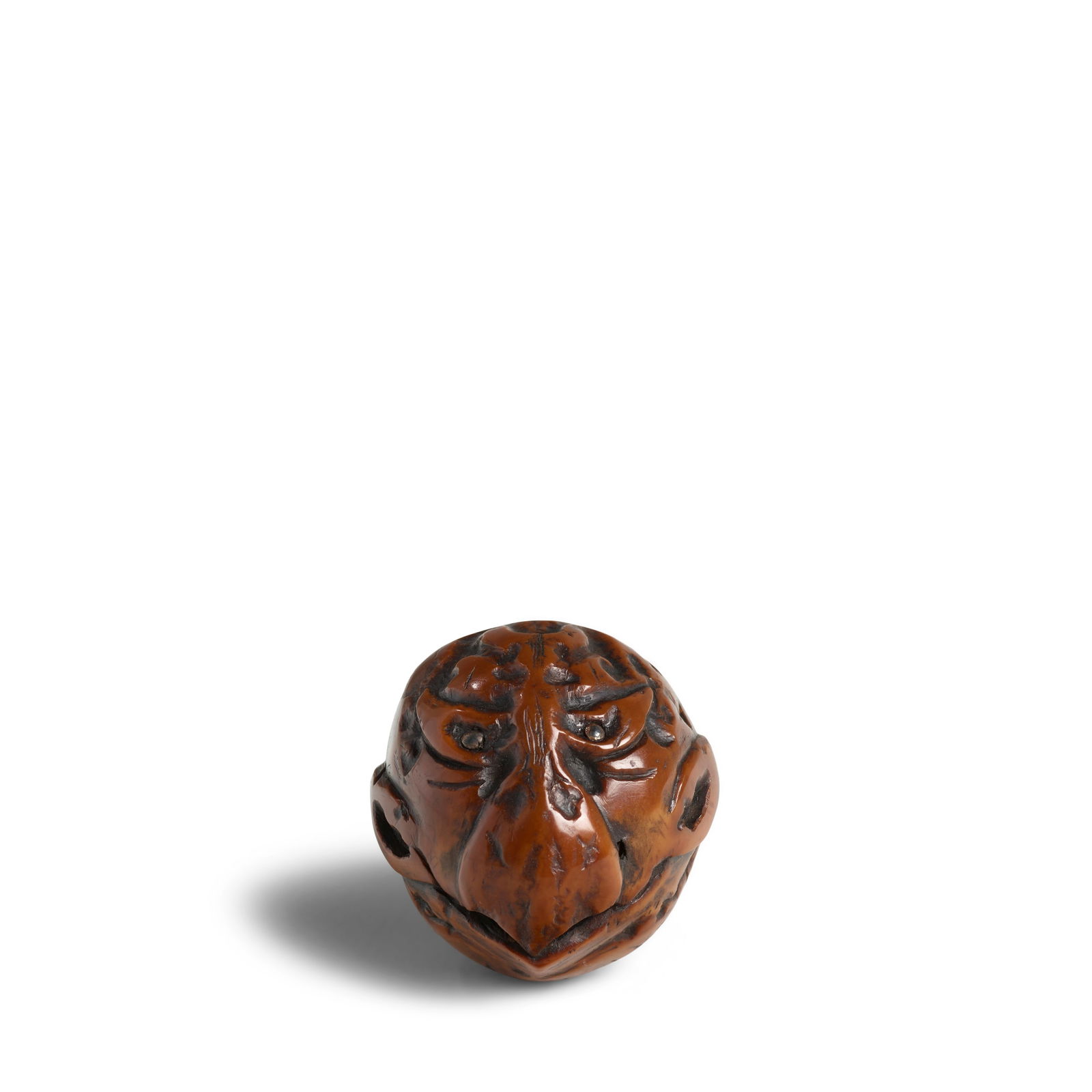 OZAKI KOKUSAI (1835-1892) A Fruit-Nut Ojime (Fastener) of the Head of a Tengu (Mountain-Dwelling...: OZAKI KOKUSAI (1835-1892) A Fruit-Nut Ojime (Fastener) of the Head of a Tengu (Mountain-Dwelling Goblin) Edo period (1615-1868) or Meiji era (1868-1912), 19th century The goblin's head carved with a s