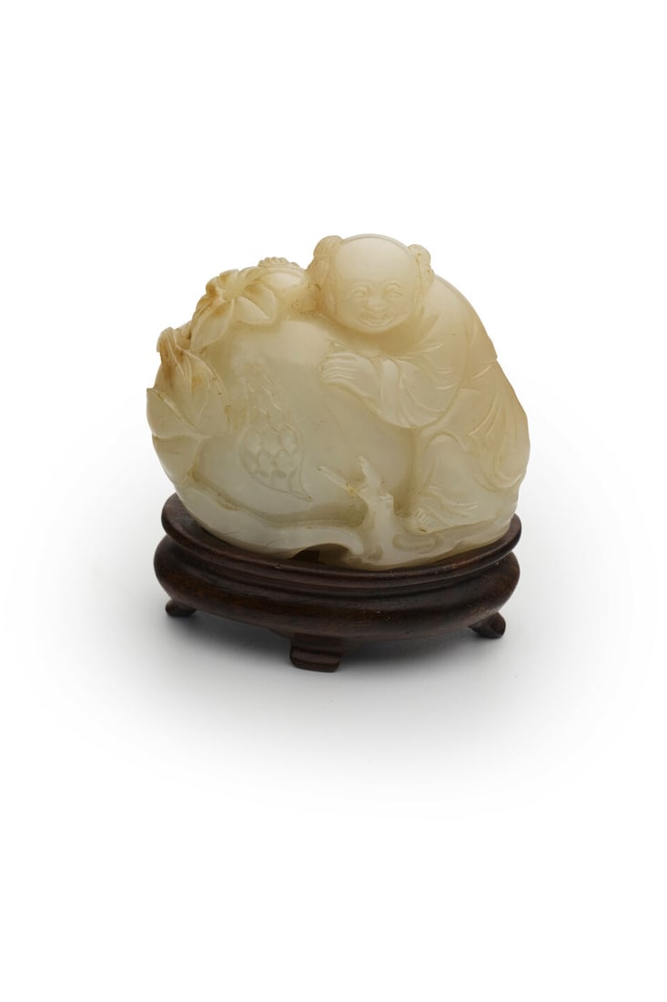 A WHITE JADE CARVING OF A CHILD PERCHED OVER A POMEGRANATE 18th/19th century - 2