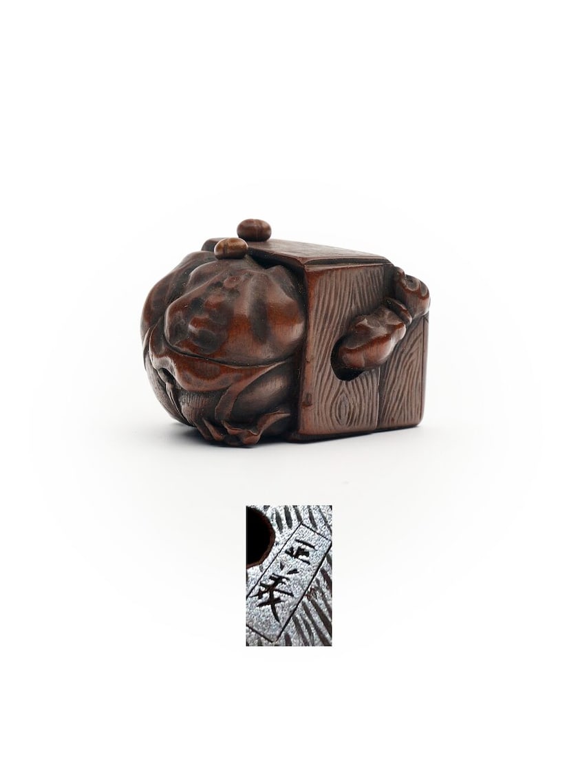 A WOOD NETSUKE OF DEMON WITH HIS HEAD IN A BOX Signed Tadayoshi [正美], Edo period: A WOOD NETSUKE OF DEMON WITH HIS HEAD IN A BOX Signed Tadayoshi [正美], Edo period 2.6cm high Footnotes: Compare with another netuske of the same subject, see The Met,