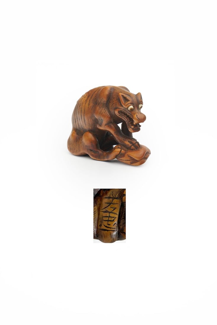 A BOXWOOD NETSUKE OF A WOLF WITH A CLAM Signed Tomotada [友忠], 19th century: A BOXWOOD NETSUKE OF A WOLF WITH A CLAM Signed Tomotada [友忠], 19th century 3.7cm high For further information on this lot please visit Bonhams.com For further information about this