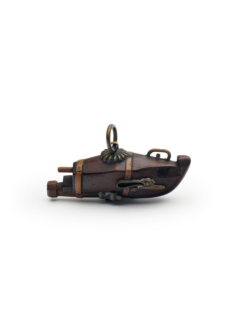 A WOODEN NETSUKE WITH METAL INLAYS OF A TANEGASHIMA GUN Meiji period: A WOODEN NETSUKE WITH METAL INLAYS OF A TANEGASHIMA GUN Meiji period with copper and brass fittings, 7.5cm high Footnotes: Provenance: Sotheby's, London, Netsuke, Inro and other Japanese Works of Art,